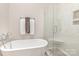 Luxurious bathroom featuring a soaking tub and a glass-enclosed shower with marble tile at 10332 Hollybrook Dr, Charlotte, NC 28277