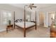 Bedroom featuring a four poster bed, neutral carpet, and adjacent doorway to the bathroom at 10332 Hollybrook Dr, Charlotte, NC 28277