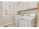 Bright laundry room with white washer and dryer, white cabinets, and window with white shutters at 10332 Hollybrook Dr, Charlotte, NC 28277