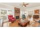 Comfortable living room featuring a brick fireplace, hardwood floors, and seamless flow to the kitchen and dining area at 10332 Hollybrook Dr, Charlotte, NC 28277