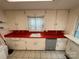 A well-equipped kitchen with red countertops, cabinets, and a sink at 10516 Hambright Rd, Huntersville, NC 28078
