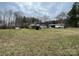 Spacious grassy yard with multiple outbuildings for storage or hobbies, surrounded by trees at 10516 Hambright Rd, Huntersville, NC 28078
