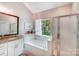 Relaxing bathroom with a soaking tub, separate shower, and bright window at 11003 Pale Hickory Ln, Charlotte, NC 28215