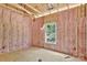 Unfinished bedroom featuring wall insulation, a window, and wood flooring at 1235 E Poplar St, Conover, NC 28613