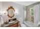 Bathroom featuring bathtub with showerhead, decorative mirror, and a dark vanity at 1327 Cedarwood Ln, Charlotte, NC 28212