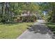 Landscaped home with long driveway leading to a white-fenced backyard and mature trees at 1327 Cedarwood Ln, Charlotte, NC 28212