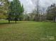 Large grassy backyard with mature trees, offering a serene outdoor space at 13316 E Rocky River Rd, Davidson, NC 28036