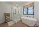 Bright bathroom featuring a glass shower, freestanding tub, wood-look floors, and natural light from the window at 13625 Buster Rd, Stanfield, NC 28163