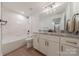 Modern bathroom featuring marble countertops, a shower-tub, and white cabinetry with gold hardware at 13625 Buster Rd, Stanfield, NC 28163
