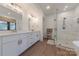 Bathroom with double vanity and white cabinetry next to the glass shower, freestanding tub, and open shelving unit at 13625 Buster Rd, Stanfield, NC 28163