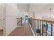 Hallway with wood floors and a metal railing leading to a living room with a fireplace and tv at 13625 Buster Rd, Stanfield, NC 28163