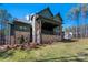 Beautiful home exterior features a stone-accented patio, green siding, lush lawn, and mature trees in a serene setting at 157 Silver Falls Dr, Troutman, NC 28166