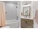 This bathroom has a tiled shower and bathtub with a modern vanity with a square mirror and updated hardware at 2011 Trailwood Dr, Matthews, NC 28104