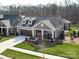 Charming single-story home featuring a two-car garage, dormer windows, and inviting front porch with a landscaped garden at 2011 Trailwood Dr, Matthews, NC 28104