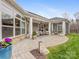 This spacious stone patio has covered seating, potted plants, manicured lawn, and access to the home's interior at 2011 Trailwood Dr, Matthews, NC 28104