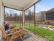 This relaxing screened porch offers a peaceful outdoor setting with cozy chairs and a view of the landscaped yard at 2011 Trailwood Dr, Matthews, NC 28104