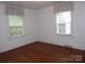 Bedroom featuring hardwood floors and two windows with striped curtains for natural light at 2815 Glendale Rd, Charlotte, NC 28209
