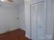 Bedroom with hardwood floors, white paneled walls, and a closet with louvered doors at 2815 Glendale Rd, Charlotte, NC 28209
