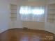 Living room with hardwood floors, built-in shelving, and natural light from shuttered windows at 2815 Glendale Rd, Charlotte, NC 28209