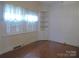 Living room featuring hardwood floors, built-in shelving, and natural light from shuttered windows at 2815 Glendale Rd, Charlotte, NC 28209