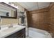 Compact bathroom with a dark vanity, decorative mirror, and tiled shower/tub with shelves and storage at 2819 Blythe Rd, Waxhaw, NC 28173