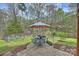 Landscaped backyard patio with a garden, dining table with umbrella, and lush greenery at 2819 Blythe Rd, Waxhaw, NC 28173