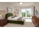 Serene bedroom with neutral carpet, a plush green headboard, natural lighting and a stylish wooden dresser at 3003 Casting St # 12, Charlotte, NC 28206