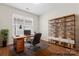 This home office features a spacious desk, comfortable chair, a shelving unit, and ample natural light at 3104 Streamhaven Dr, Indian Land, SC 29707