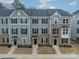 A detailed view of the townhome exteriors featuring stone accents, neutral paint, and black window shutters at 3104 Timber Mill Dr, Matthews, NC 28104