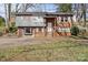 Charming split-level home featuring a brick facade, gray siding, and a well-manicured lawn at 326 Whispering Pines Dr, Charlotte, NC 28217