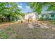 Large backyard with mature trees, landscaping, and patio. Features a fire pit and detached buildings at 36 Yorktown Nw St, Concord, NC 28025