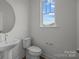 Cozy powder room with a round mirror, pedestal sink, and natural light from the bright window at 4127 Walking Ridge Rd # 53, Charlotte, NC 28208
