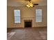 Carpeted living room showcasing a cozy fireplace with a decorative mantelpiece, complemented by natural lighting from two windows at 4612 Waterbell Ln, Waxhaw, NC 28173
