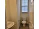 Cozy powder room with a pedestal sink, toilet, window, and neutral color scheme; clean and functional at 4612 Waterbell Ln, Waxhaw, NC 28173