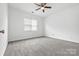 Neutral bedroom featuring a ceiling fan, carpet flooring, and a large window at 5959 Pale Moss Ln, Charlotte, NC 28269