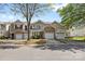 Street view of townhomes with stone accents, one-car garages, and landscaped front yards under a blue sky at 5959 Pale Moss Ln, Charlotte, NC 28269