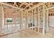 Open-concept living room during construction, featuring wooden framing, pink insulation, and a glimpse of the outdoors through windows at 8455 W Nc 152 Hwy, Mooresville, NC 28115