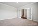 Versatile room with plush carpeting, leading through French doors to staircase at 9940 Manor Vista Trl, Kannapolis, NC 28027