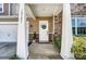 Inviting front porch featuring stone accents, a white front door adorned with a wreath, and lush landscaping at 10321 Solar Way, Charlotte, NC 28278