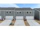 Rear exterior of new townhomes featuring garages, AC units, and gray siding at 104 Ciara Pl # B, Mooresville, NC 28117