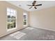 Neutral bedroom features plush carpeting, ceiling fan, and two windows offering natural light and neighborhood views at 1102 Balcorn Pl, Charlotte, NC 28214