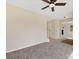 Spacious carpeted living room, neutral walls, a ceiling fan, and a doorway to another room with backyard views at 1102 Balcorn Pl, Charlotte, NC 28214