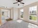 Well-lit living room with neutral walls, plush carpeting, ceiling fan, and bright windows with neighborhood views at 1102 Balcorn Pl, Charlotte, NC 28214