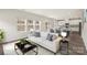 Bright living room featuring a plush white sofa, stylish décor, and an open floor plan leading into the kitchen at 117 Obadiah Ct, Troutman, NC 28115