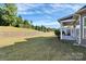 Expansive backyard featuring a retaining wall, lush greenery, and a covered porch area at 14920 High Bluff Ct, Charlotte, NC 28278