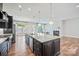 Open kitchen with granite island, stainless appliances, and hardwood floors, leading to a cozy living space at 14920 High Bluff Ct, Charlotte, NC 28278