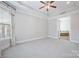 Spacious Primary bedroom with a ceiling fan, neutral carpeting, and a doorway to a spa-like bathroom at 14920 High Bluff Ct, Charlotte, NC 28278