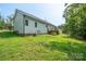 Back exterior of the home showing grass, surrounding trees, and a small deck at 1700 Ivey Ct, Maiden, NC 28650