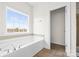 Bright bathroom featuring a soaking tub beneath a window, with an open doorway to a closet area at 2251 Barrowcliffe Nw Dr, Concord, NC 28027