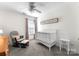 Bedroom with a white crib, comfortable chair with ottoman, and natural light at 2259 Crosscut Dr, Charlotte, NC 28214